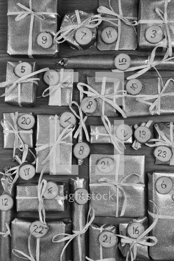 Advent calendar with twenty four silver presents on grey wood