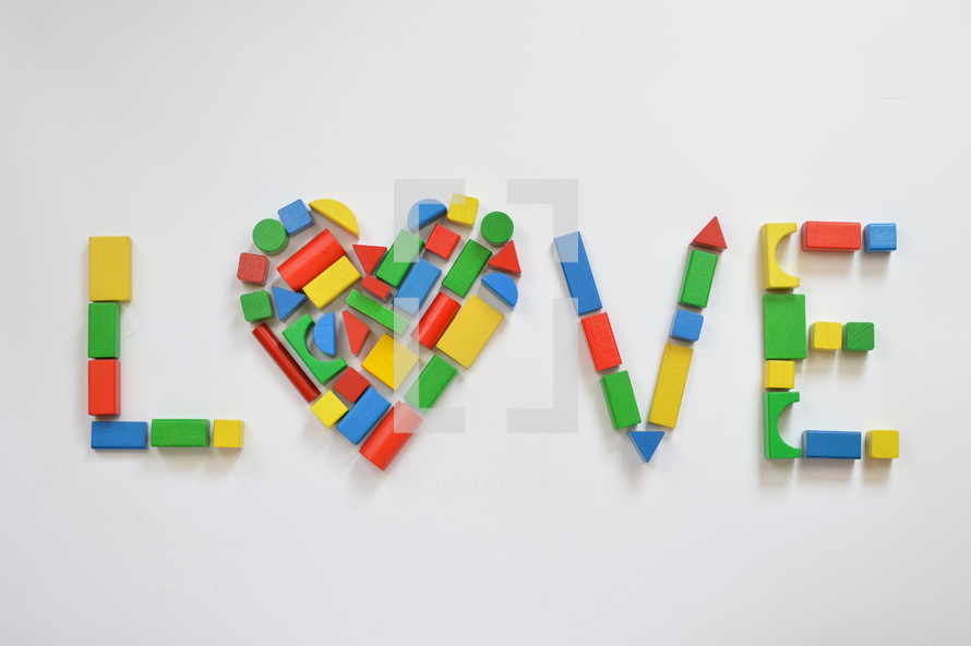 colorful wooden toy blocks shaping the form of a heart as an O in the word LOVE