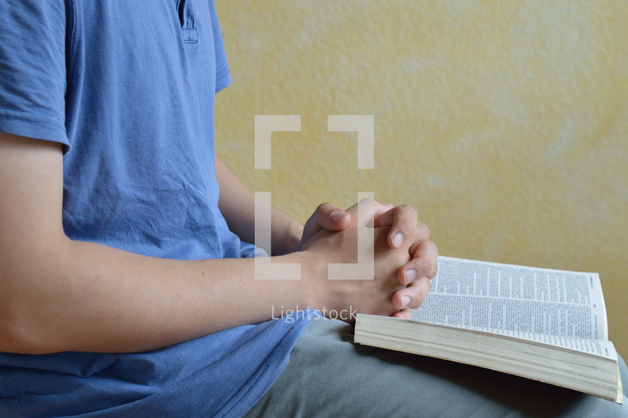 man praying with a Bible in his lap 