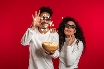 Young couple in cinema in 3d glasses watching comedy movie eating popcorn
