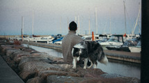 Woman with her dog sitting at the dock