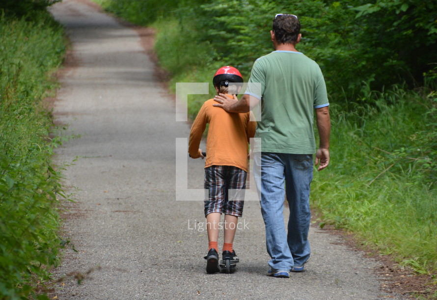 father and son walking on a trail through the woods 