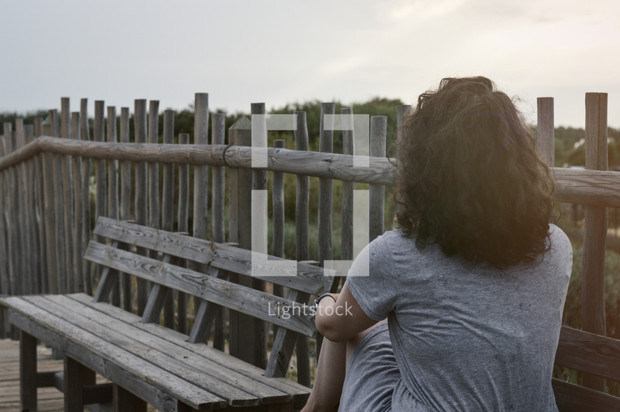 a woman sitting on a boardwalk thinking 