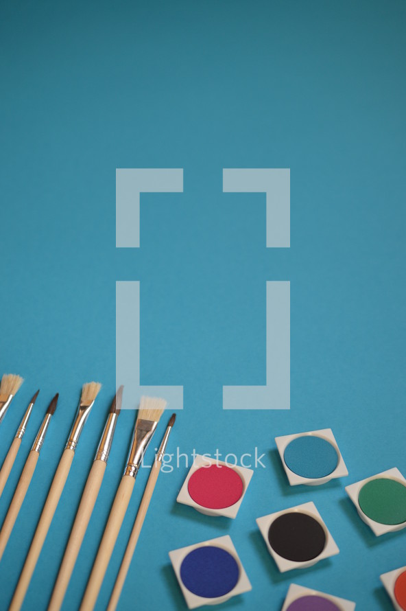 paints and paint brushes on a blue background 