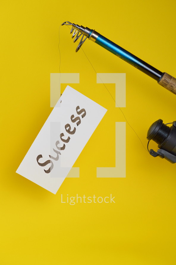 A fishing pole with a piece of paper with the word success on it 