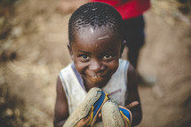 smiling African child holding shoes 