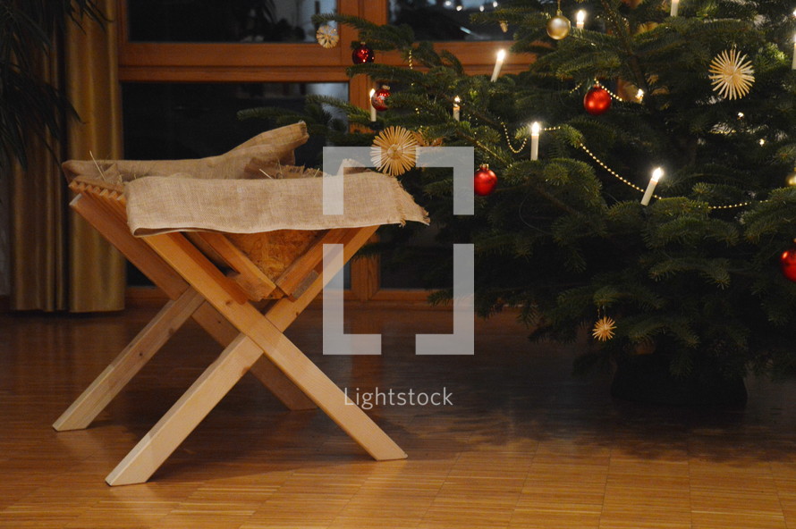 a manger in front of a Christmas tree 