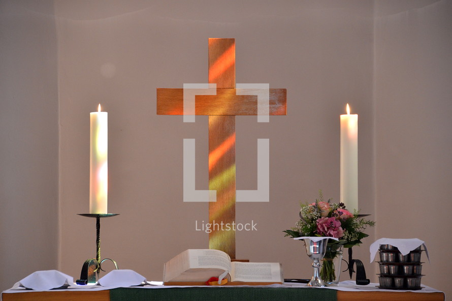 sunlight falling through a stained-glass window and illuminating a wooden cross at the altar.