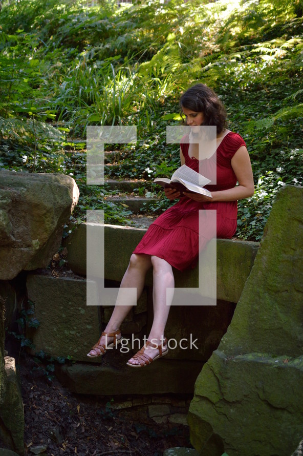 woman sitting in a forest reading a Bible 