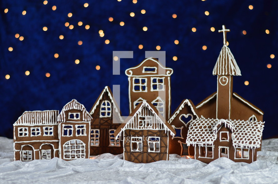 home made delicious sweet traditional gingerbread town with bokeh sky out of blue velvet and christmas lights as advent decoration