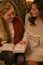 Two young women reading the Bible together.