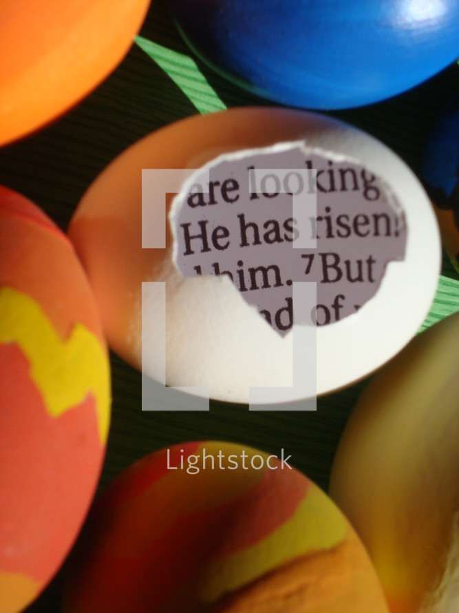 eggshell with a piece of the bible inside saying: HE HAS RISEN! between colored eggs