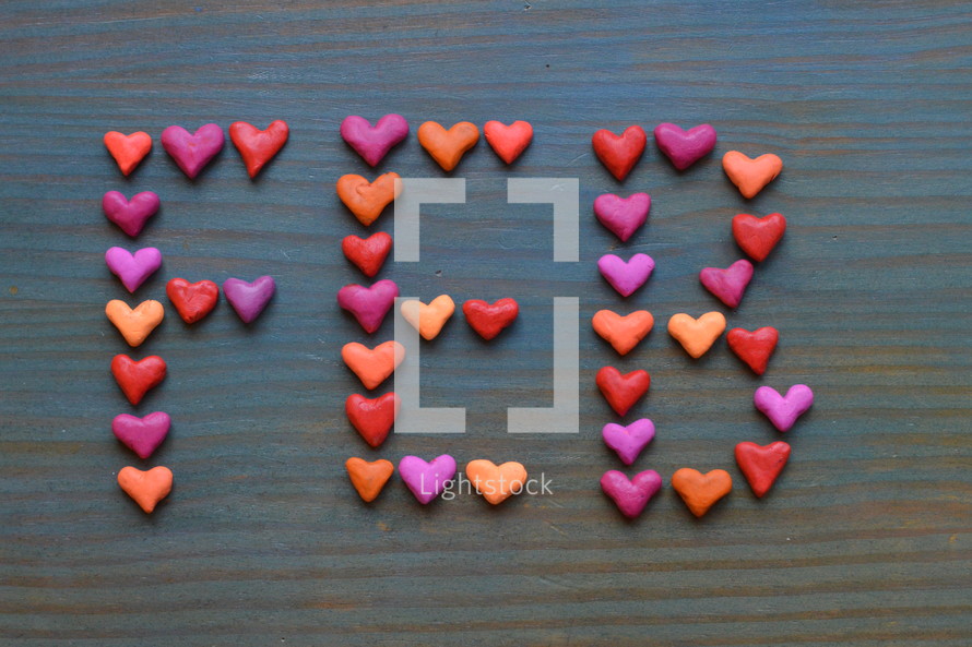 The word FEB for February written with many little colorful clay hearts on cyan wooden background 