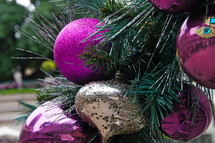 Purple and gold ball ornments hanging from pine Christmas tree.