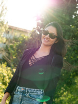 Woman in black top and jean skirt with sunglasses
