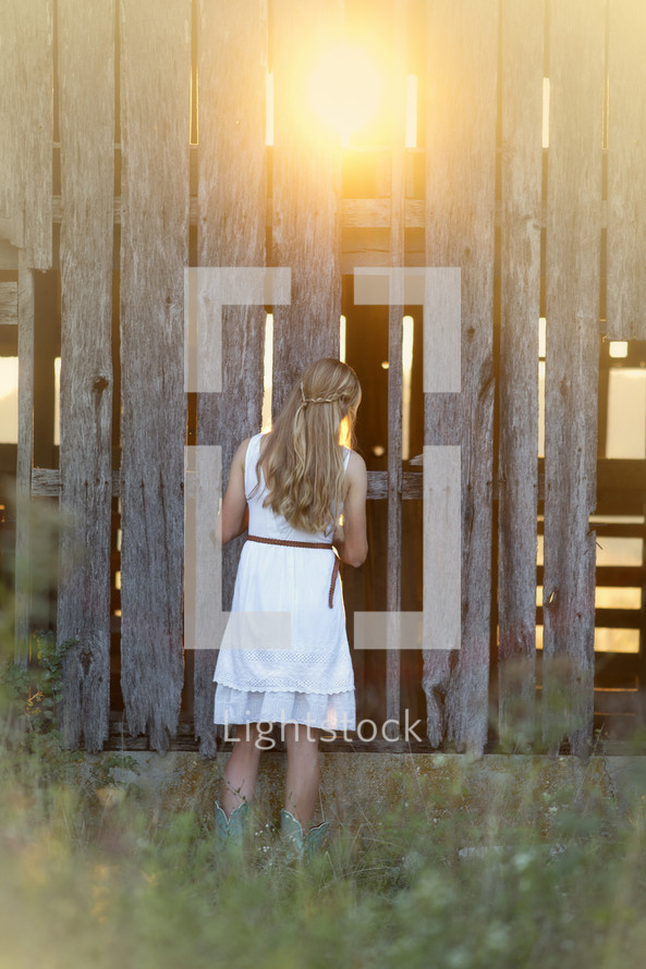 woman looking into an old weathered barn 