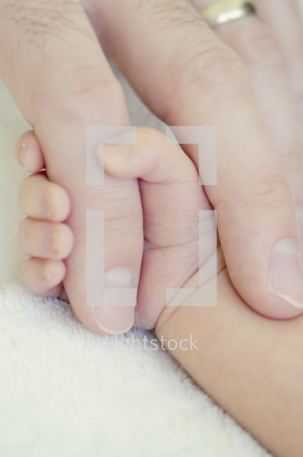 infant holding father's hand