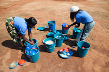 Woman washing dishes in buckets in Malawi, Africa. 