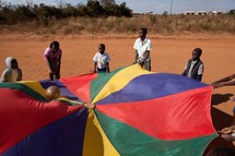 children playing with a ball and parachute in Malawi, Africa. 