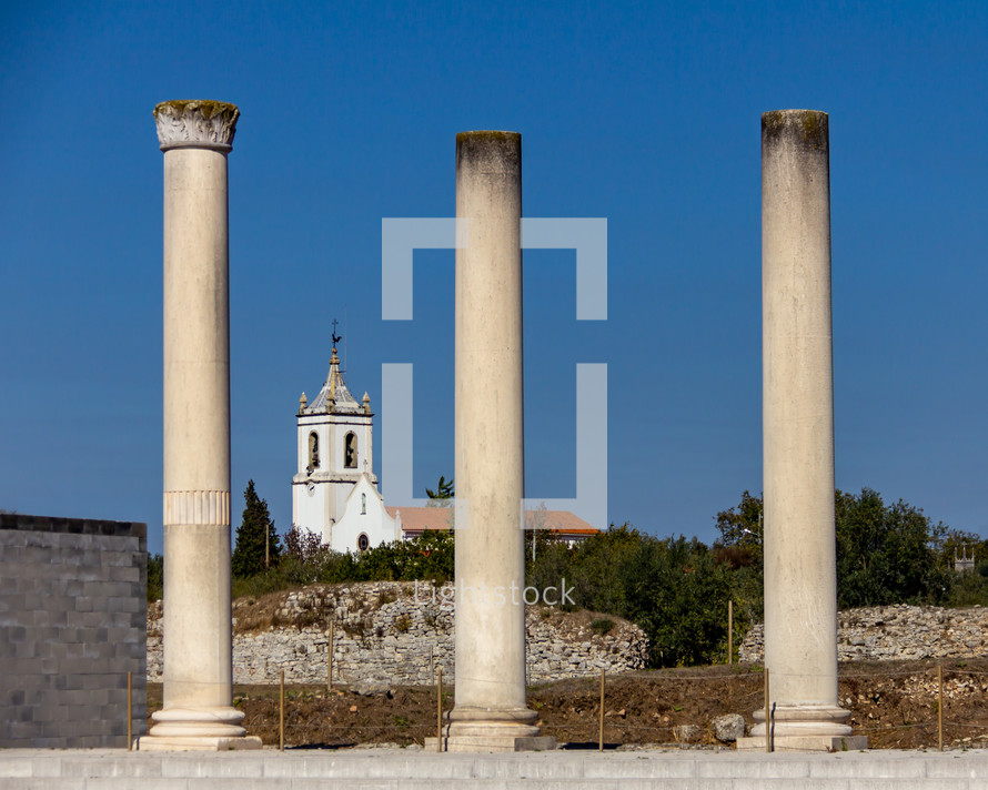 Church framed by Roman Columns at  Conimbriga in Portugal under a cloudless blue sky