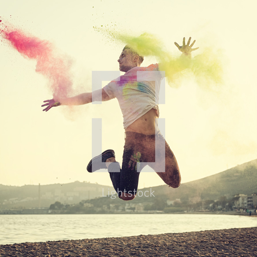 young man jumping with energy and colored powder.