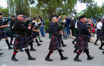 A parade of Scottish men wearing kilts and playing bag pipes in the Scottish Highland Festival where Scotland and Scottish descendants gather together every year to celebrate their heritage. 
