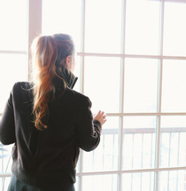 a woman with a ponytail looking out a window 