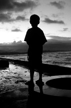 a young boy standing near water 