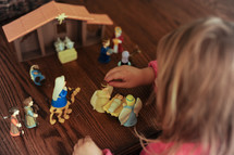a little girl playing with a toy nativity scene 