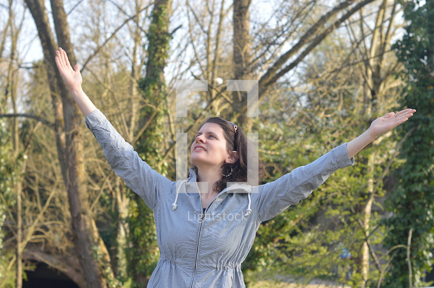 Woman with raised arms in adoration outdoors in nature.