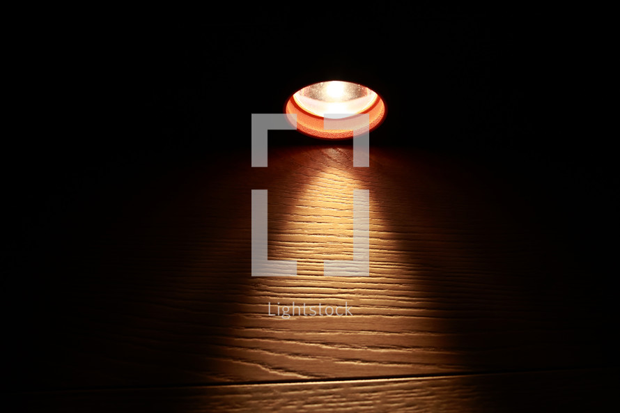 Flashlight and a beam of light in darkness. A modern led light with bright projection on dark wood table. Surface with copy space. power outage. collapse of the power system