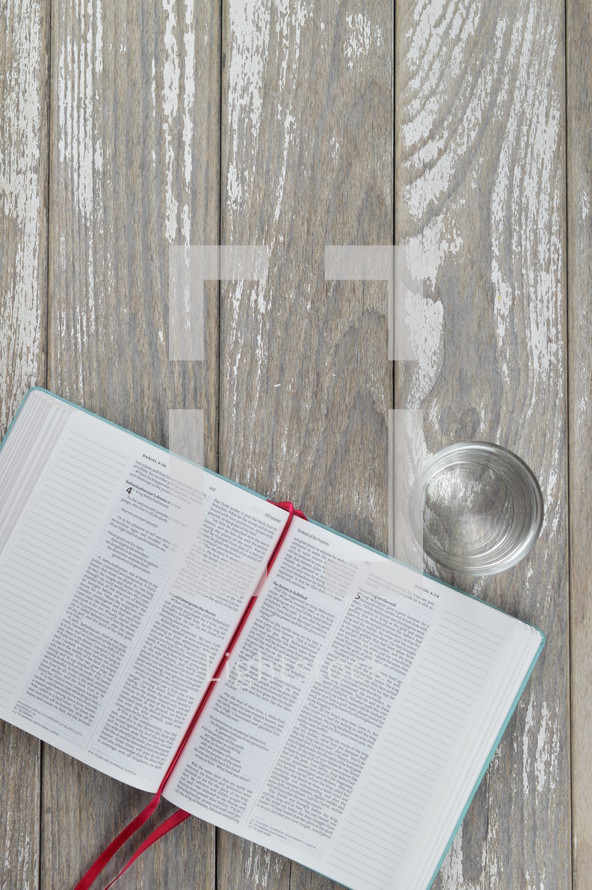 open Bible and glass on a wood background 