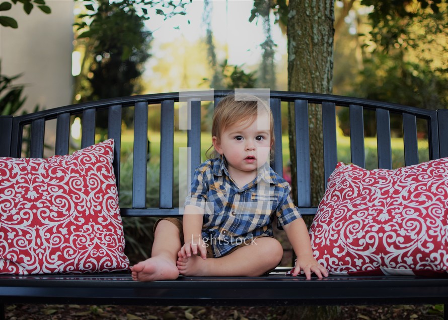 a toddler boy sitting on a bench 