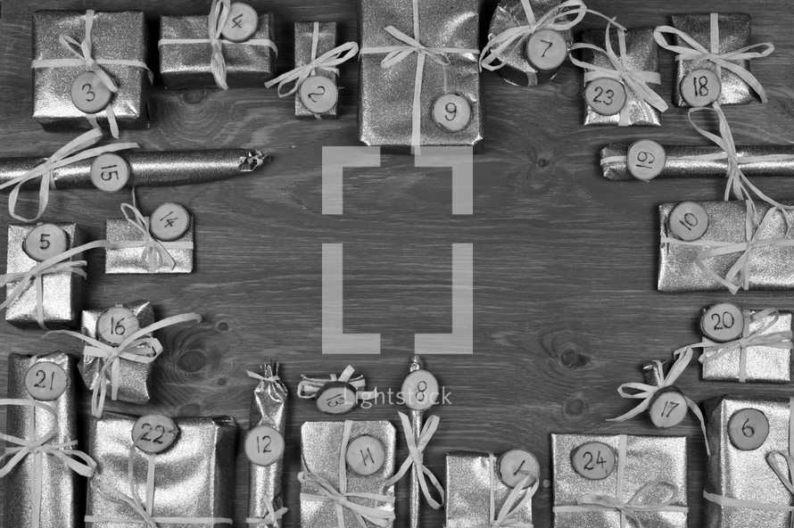 Frame of advent calendar with twenty four silver presents on grey wood