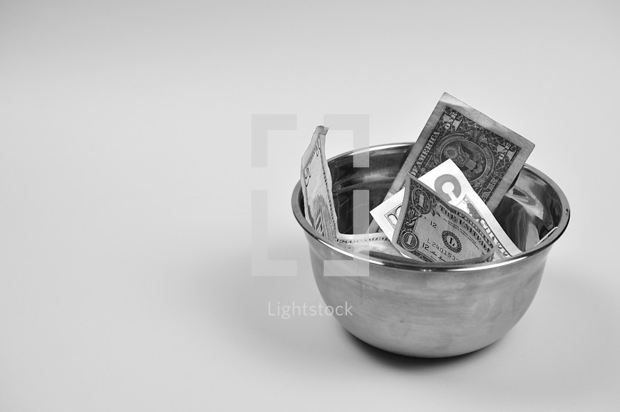dollar bills in a bowl on a white background 