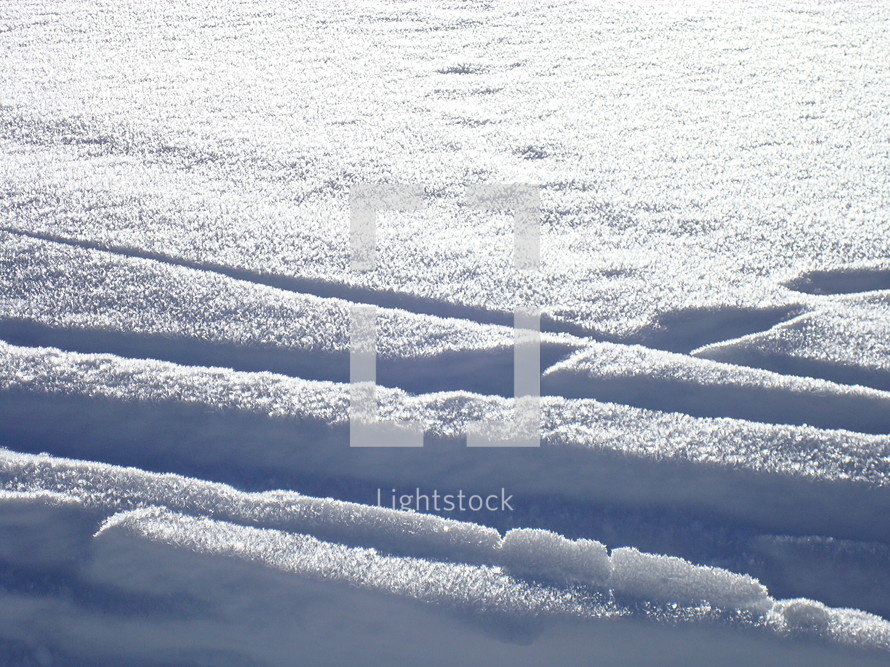 tracks in the snow at a bright day with sunshine. 
