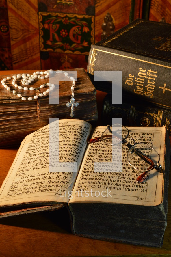 a rosary and reading glasses on an old Bible 