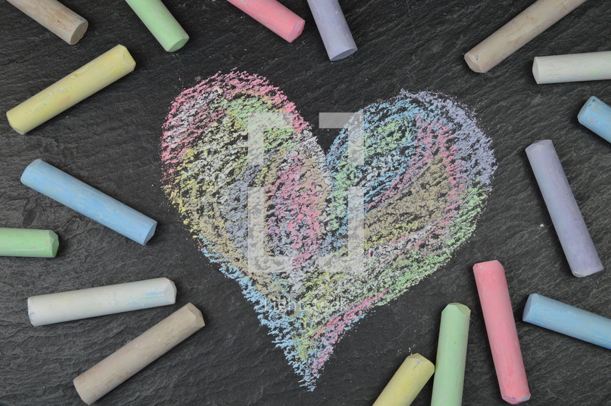 heart shape in sidewalk chalk on slate surrounded with sticks of chalk 
