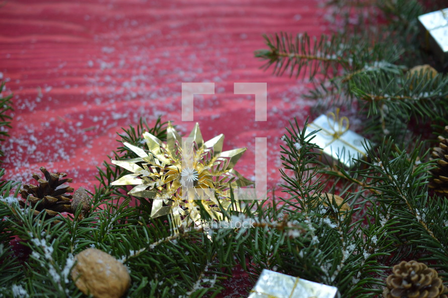 pine needles, ornaments, pine cones, and snow on a red background 