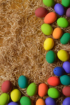 border of colorful Easter eggs on straw 