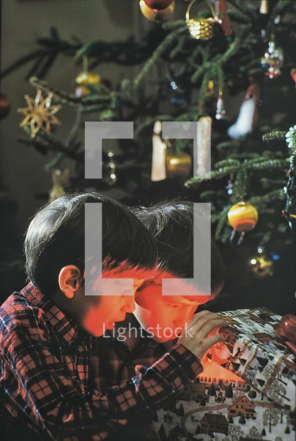 Two young boys look into a Christmas box at light