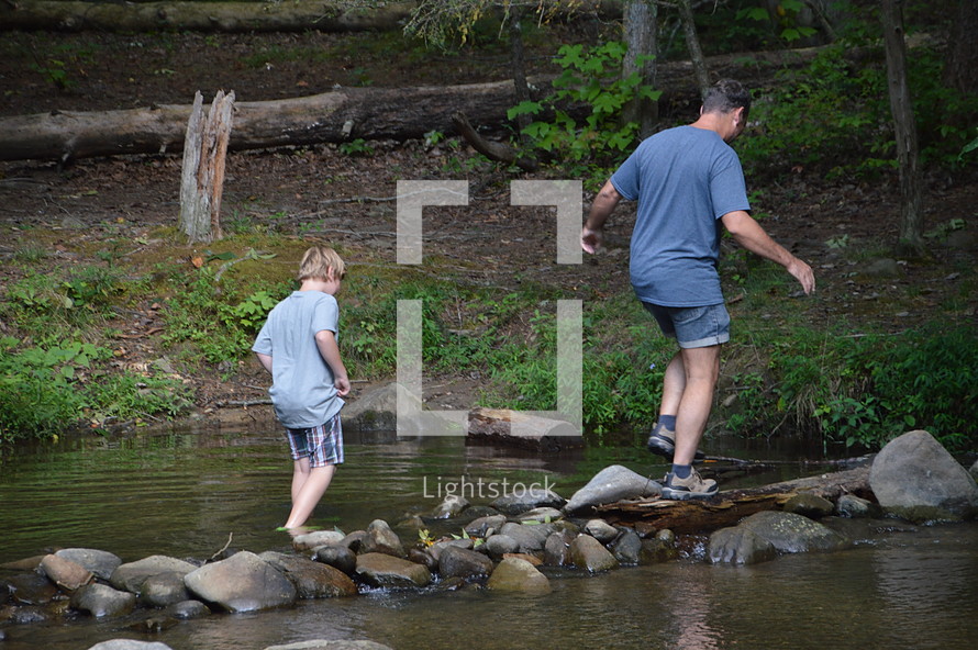 father and son exploring a stream 