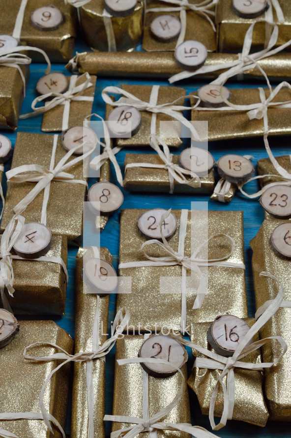 Advent calendar with twenty four golden presents on teal wood