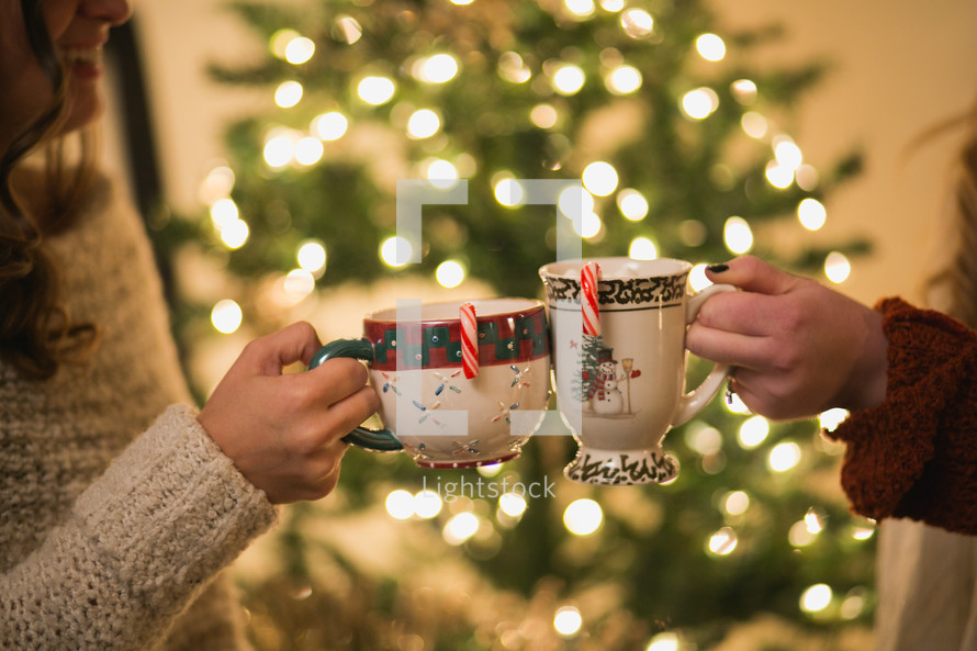 Two women make a toast with their Christmas cups.