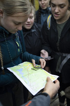 People huddled around a trail map holding a compass 