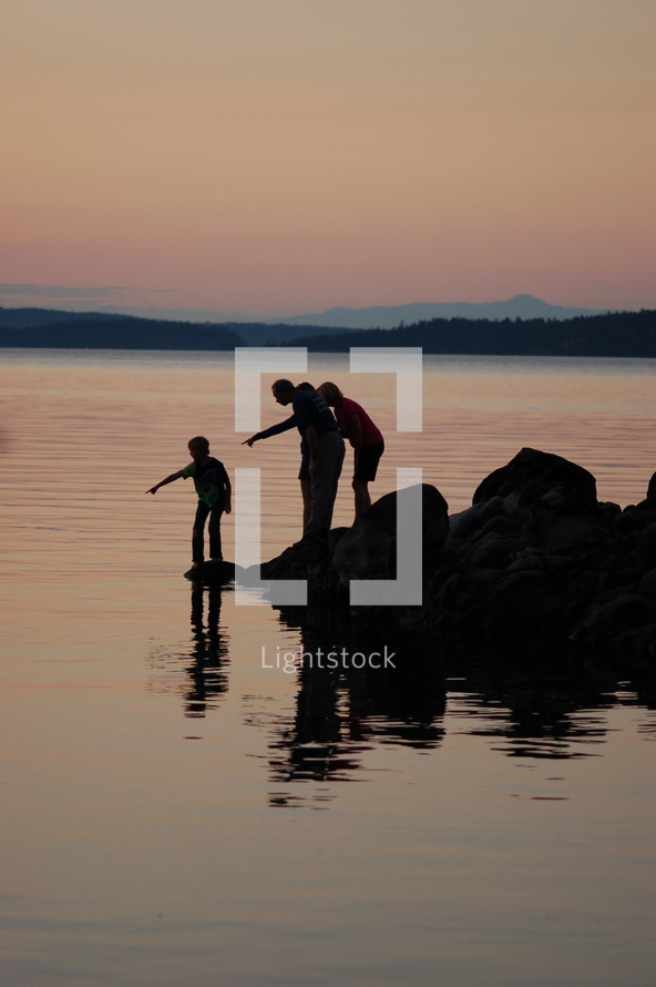 family at a lake pointing to the water 
