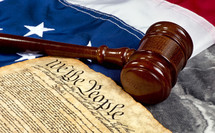 Wooden gavel on top of American flag and Bill of Rights document