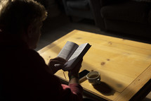 Man reading and drinking coffee at a table