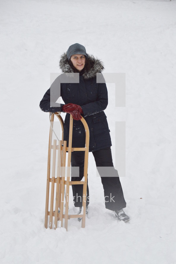 woman standing with a sled in snow 