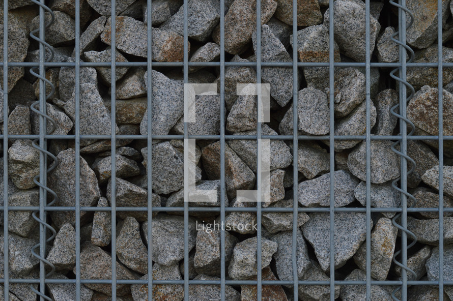 stones behind metal fencing 